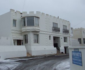 Western Esplanade seafront property in Hove in the snow. White building with castellated walls.