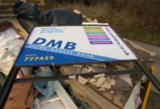 DMB Solutions (building firm) sign lying discarded on a heap of rubble