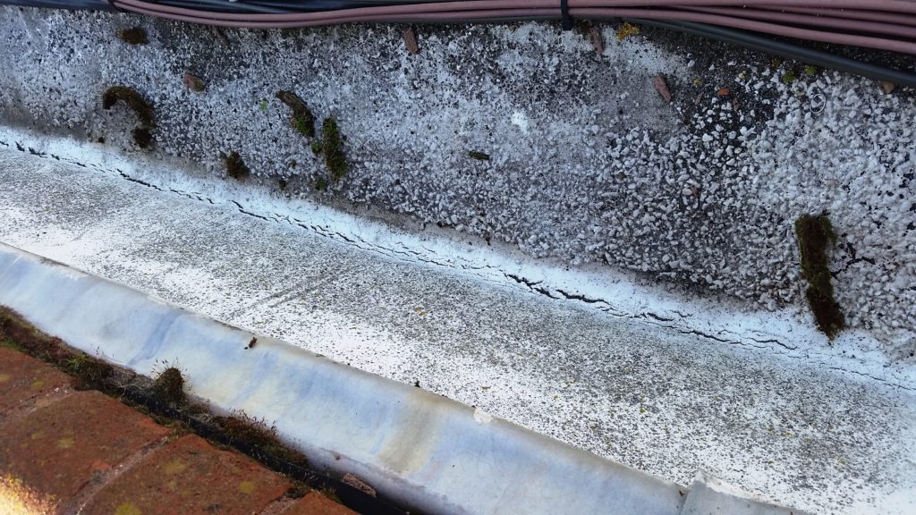 Close Up of Cracking to Silver Solar Reflective Coating on an Asphalt Roof