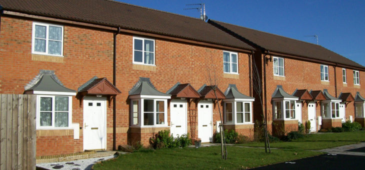 A street of small, cottage-style red brick houses against a blue sky