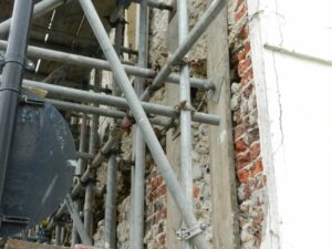 Red brick wall being shored up in Brighton, scaffolding